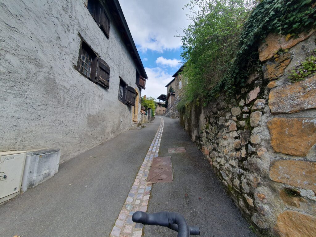 a narrow passage between a house and a stone wall, going up the village of Chamelet