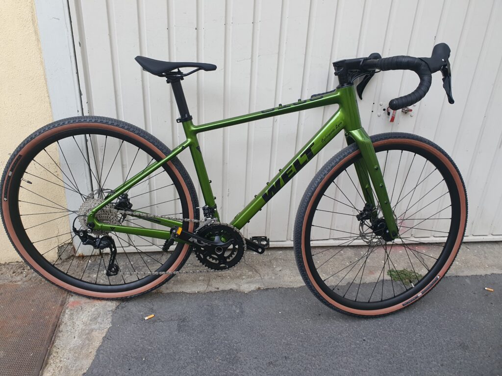 A kiwi green brand new  gravel bike in front of a white garage door